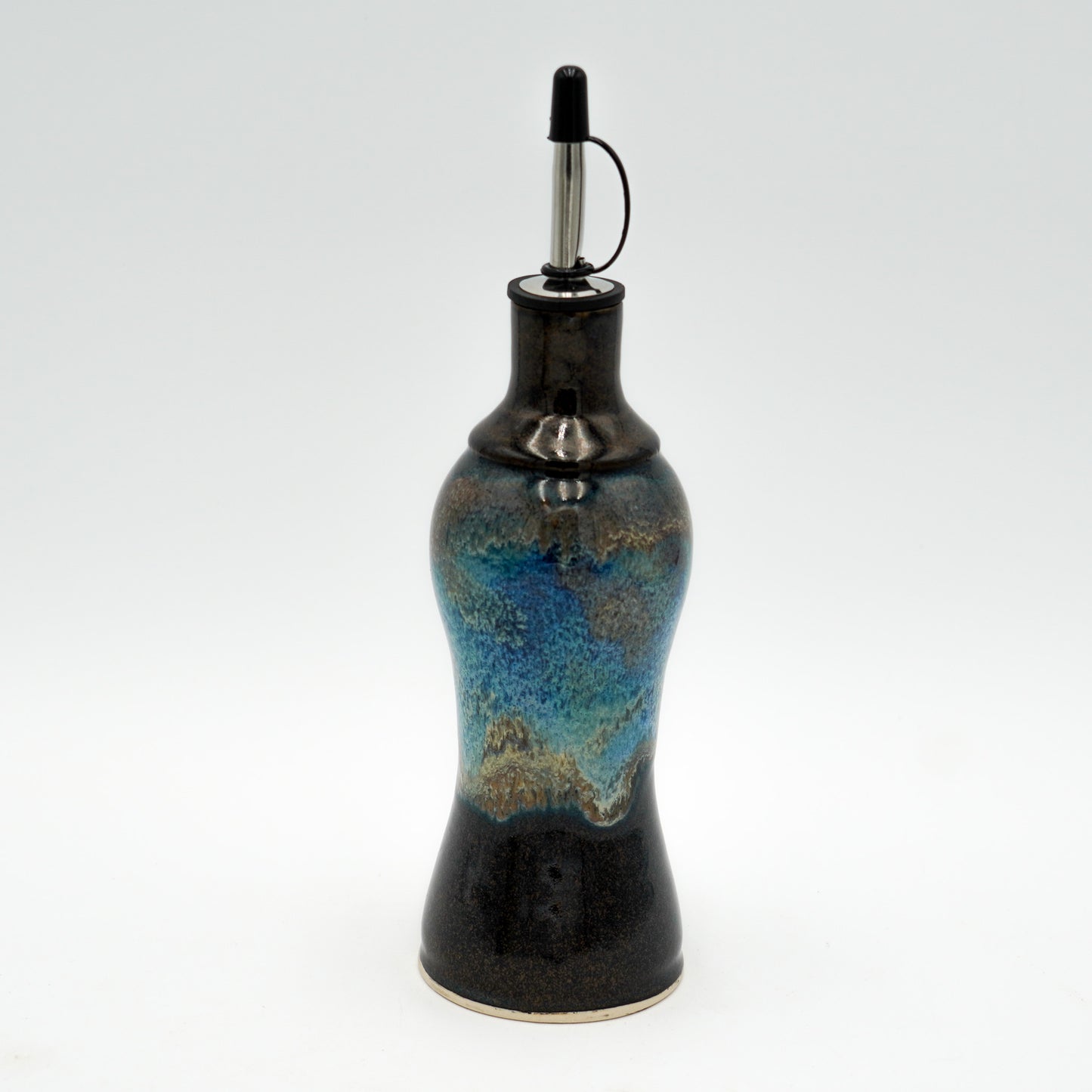 Ceramic oil bottle with blue and black design on a white background