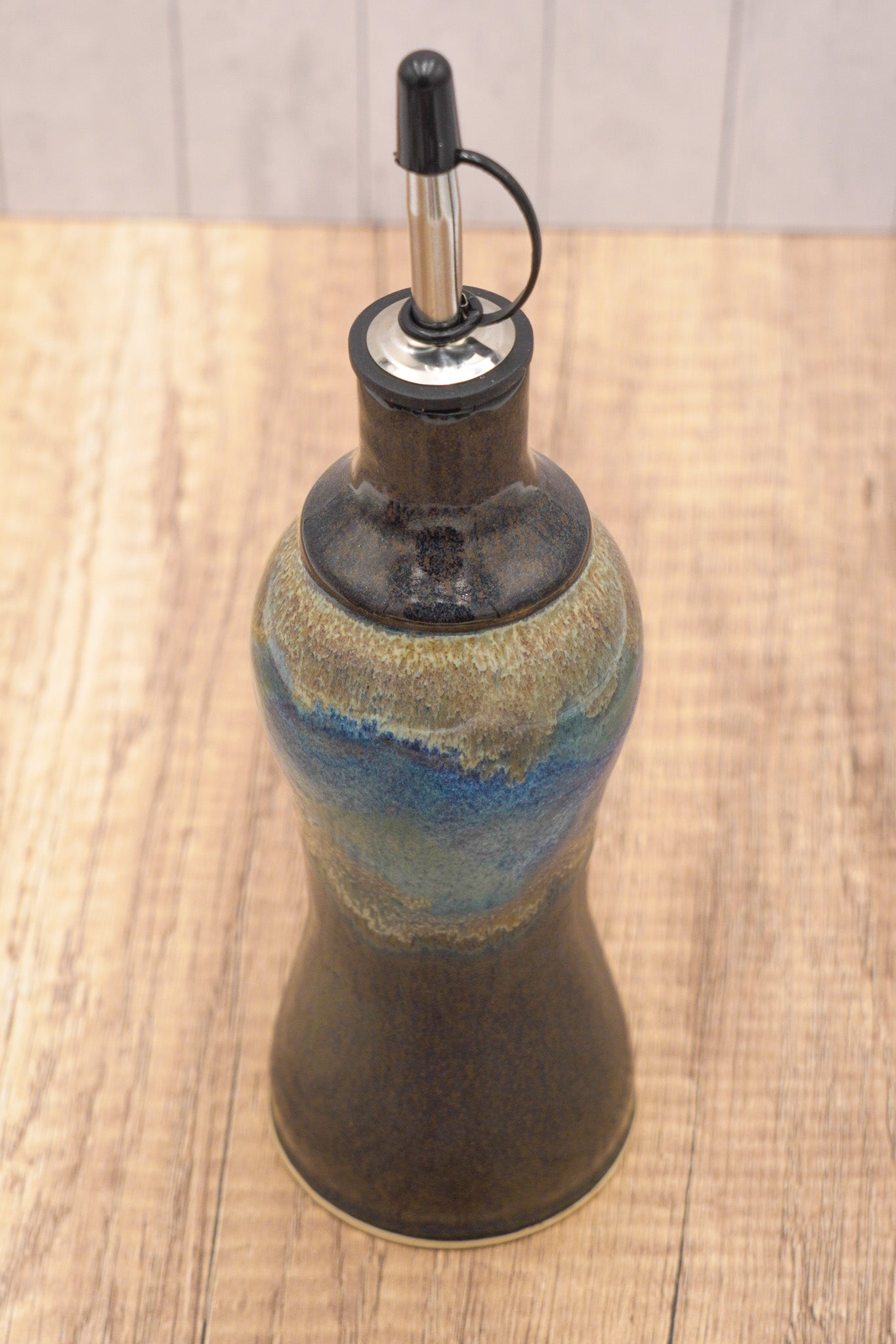 Decorative oil bottle with a blue and silver design on a wooden surface