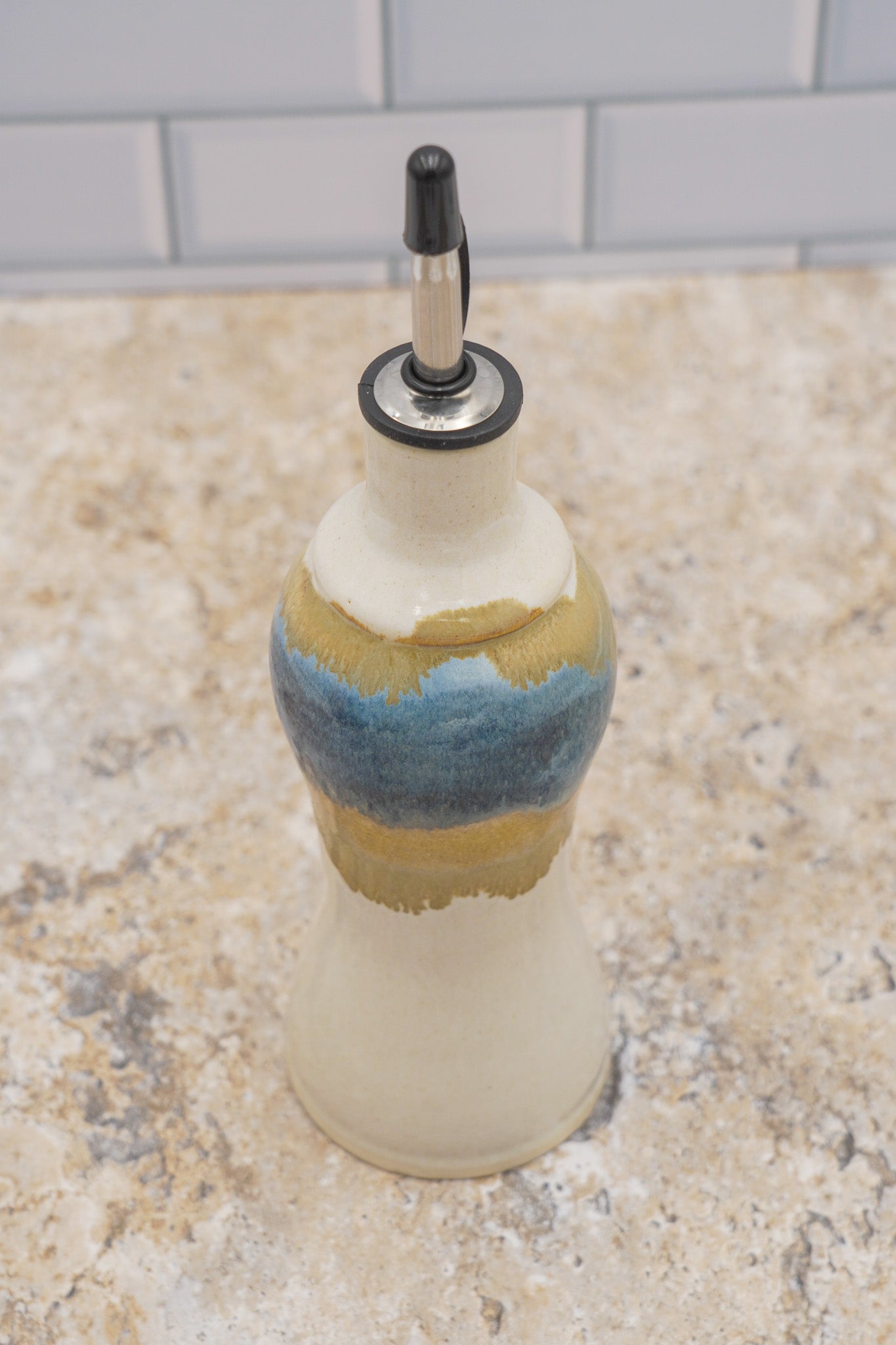 Decorative handmade pourer bottle with a painted design on a marble surface