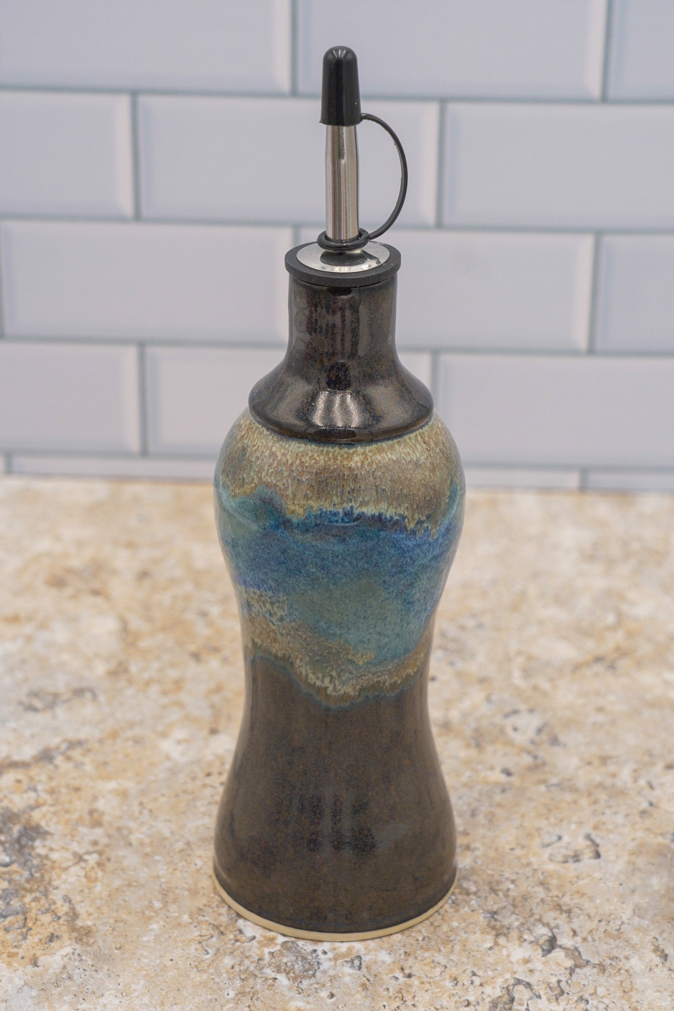 Decorative ceramic oil bottle with a blue accent on a countertop.